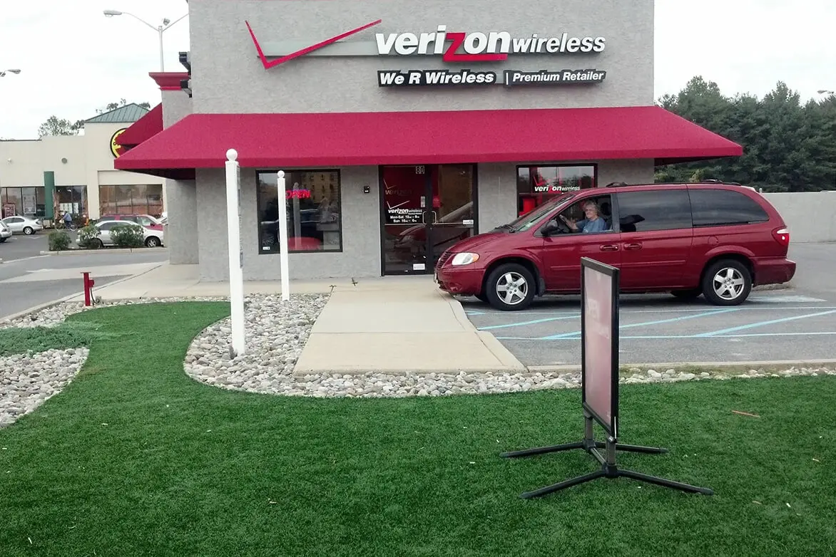A red van parked in front of a verizon wireless store.