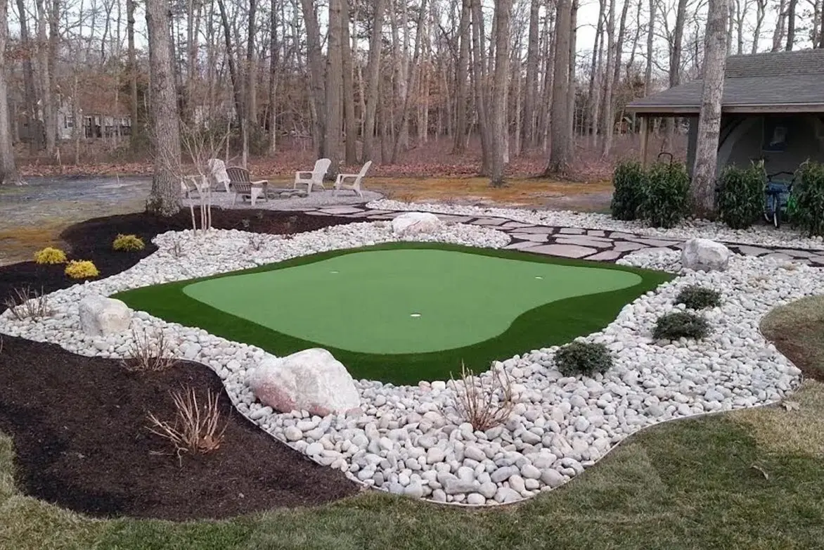 A backyard with a putting green and rocks