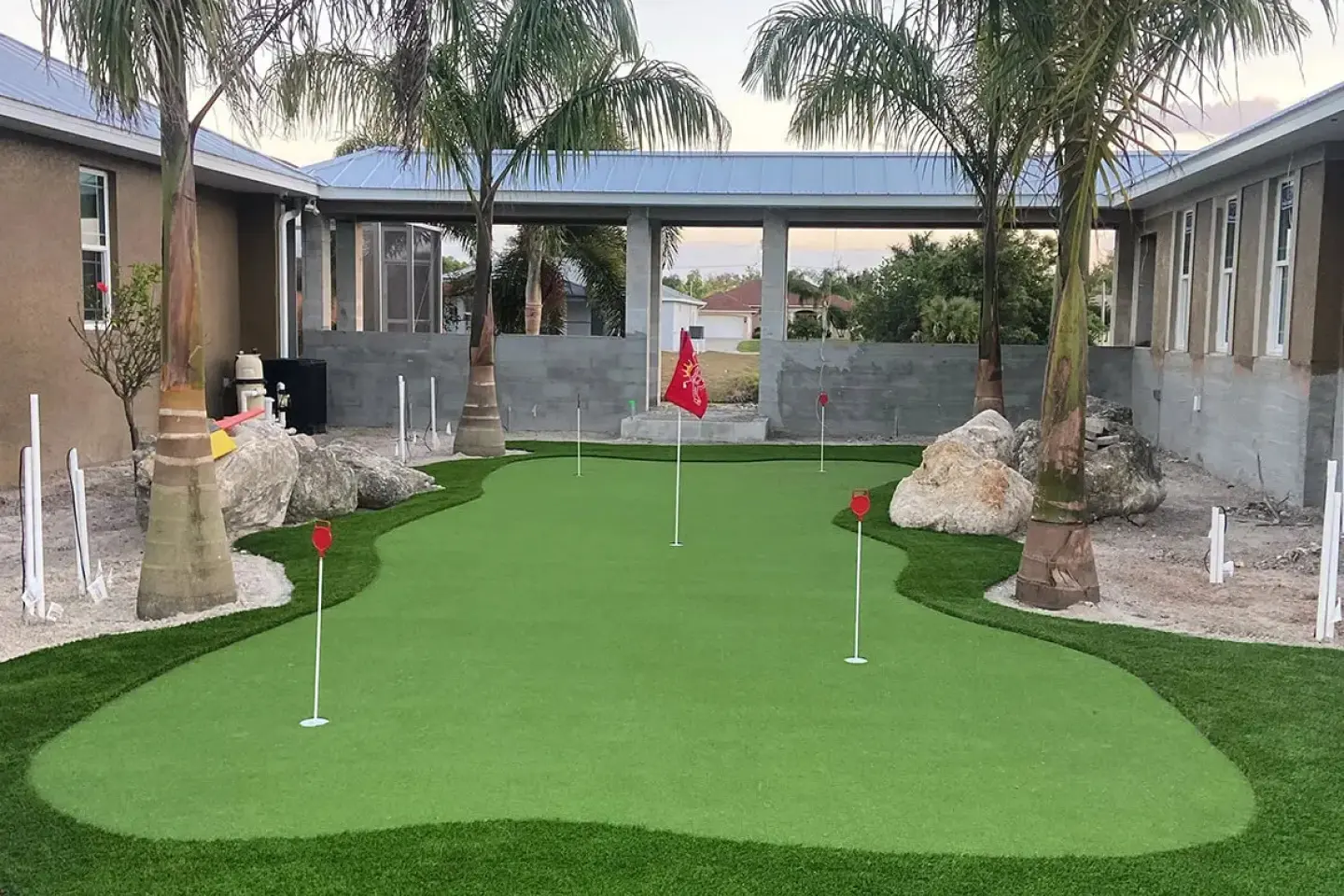 A backyard with palm trees and a putting green.