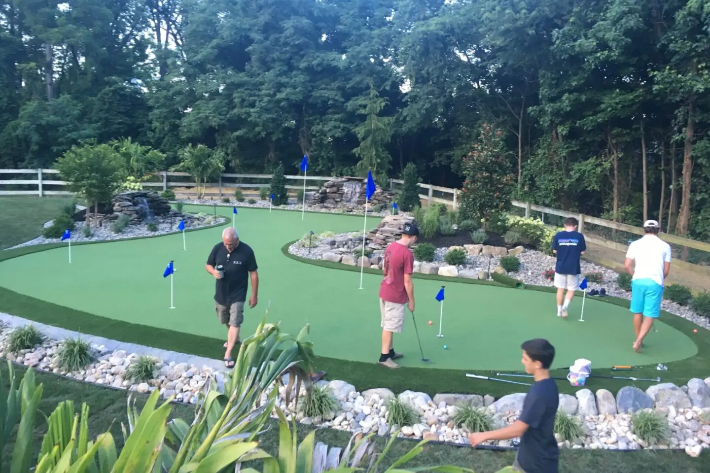 A group of people playing mini golf on the green.