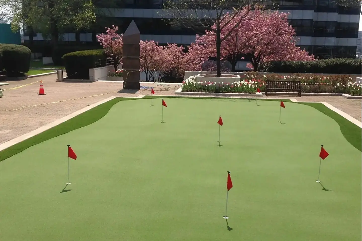 A green golf course with red flags and trees.