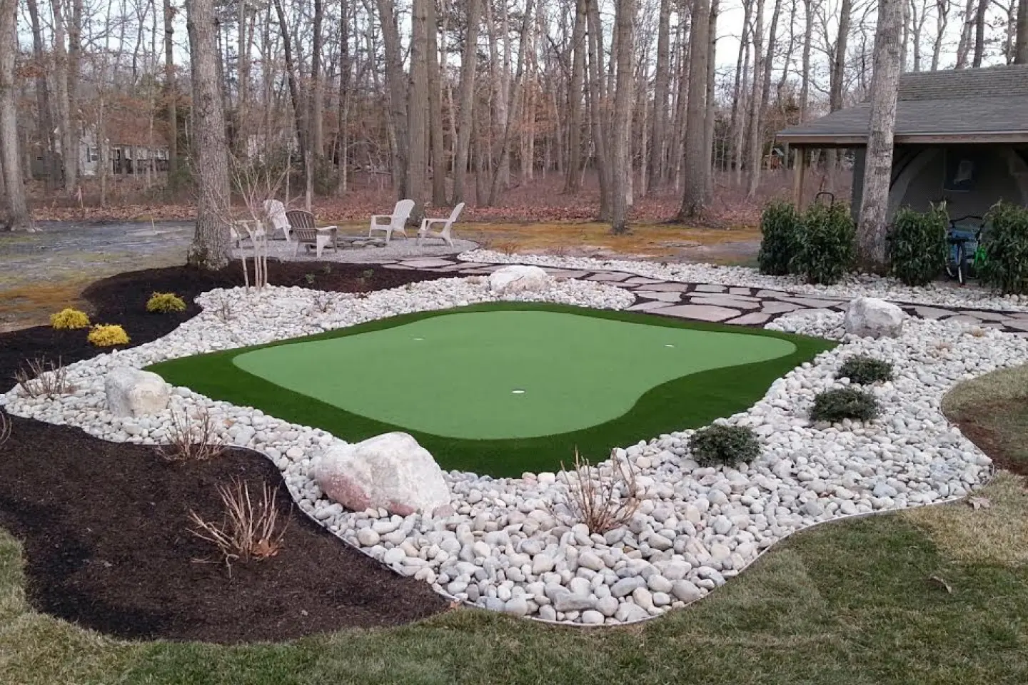 A backyard with a putting green and rocks.